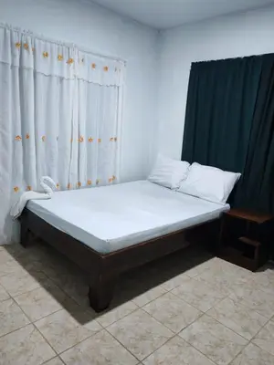 a bed sitting in a room with curtains at Nayon Vacation Home in Portegolpe