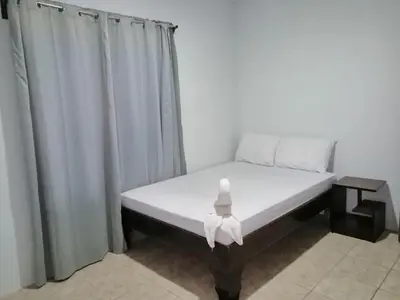 a bed in a room with curtains at Nayon Vacation Home in Portegolpe