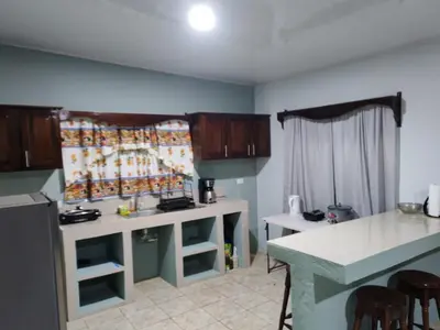 a kitchen with white counters and a counter top at Nayon Vacation Home in Portegolpe