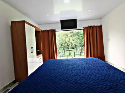 a bedroom with a blue bed and a window at The Chicken House in El Castillo de La Fortuna