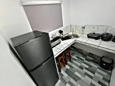 a small kitchen with a refrigerator and a table at The Chicken House in El Castillo de La Fortuna
