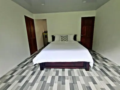 a bedroom with a large bed with white sheets at The Chicken House in El Castillo de La Fortuna