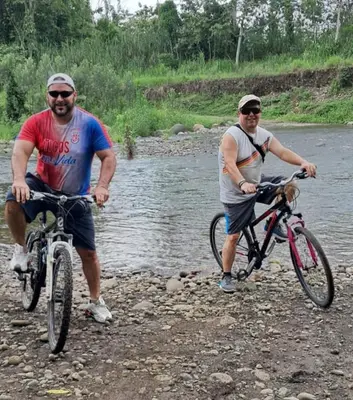 two men are standing with their bikes on a river at Tree House River in Palma