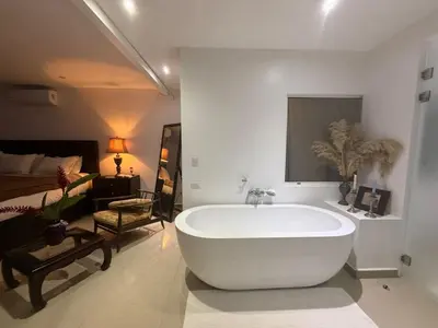 a large white bath tub in a room with a bed at Encantadora casa con piscina privada in Herradura