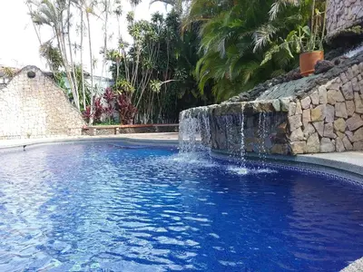 a swimming pool with a waterfall in a yard at Hotel Cibeles Resort in Heredia
