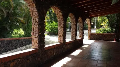 an arched walkway in a resort with a stone wall at Hotel Cibeles Resort in Heredia