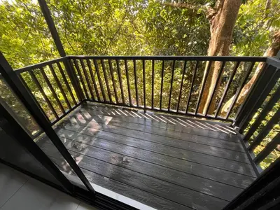 a balcony with a wooden deck with trees in the background at Hospedaje El Lago in Coronado