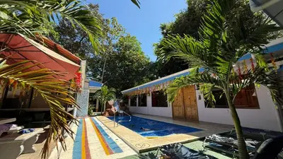 a swimming pool with a palm tree next to a building at Tres Diamantes hotel in Parrita