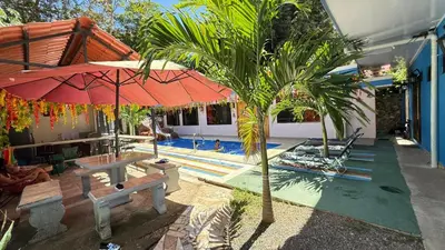 a pool with a red umbrella and a palm tree at Tres Diamantes hotel in Parrita