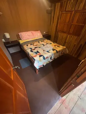 a small bed in a room with a wooden wall at Mineral River Eco Village in Tapantí