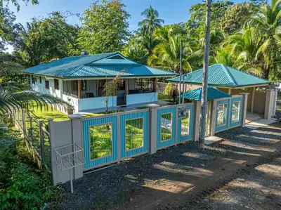 a house with a blue roof and a fence at Villa Tortuga- 3 Minute Walk to the Beach in Savegre