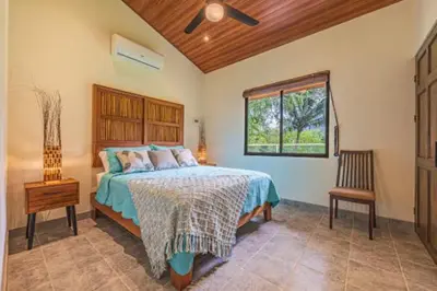a bedroom with a bed and a window and a chair at Villa Tortuga- 3 Minute Walk to the Beach in Savegre