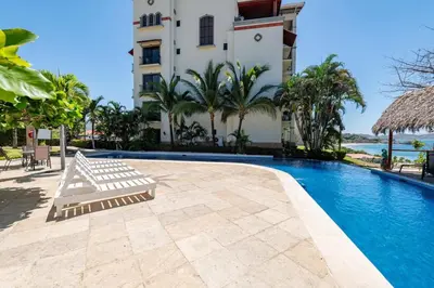 a swimming pool in front of a building at Playa Flamingo Ocean View Retreat in Playa Flamingo