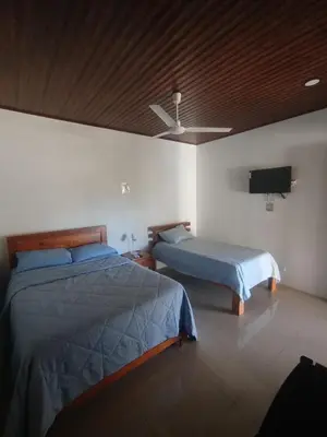 a bedroom with two beds and a flat screen tv at Las Morenas in Nosara