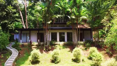 a house with palm trees in front of it at Majestic View House in Dominical, Oceanview in San Luis