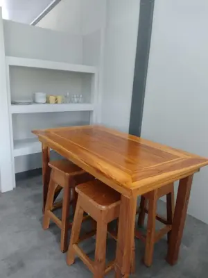 a wooden table with a pair of stools around it at Marea Place in Carrillo
