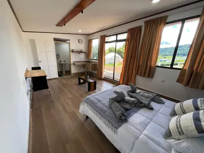 a bedroom with a large bed and large windows at Green haven in Alajuela City