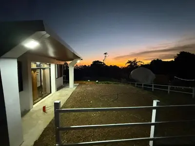 a house with a fence in front of a sunset at Green haven in Alajuela City