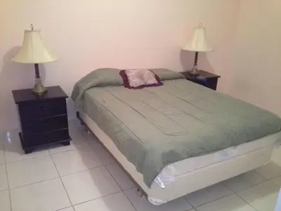 a bedroom with a bed and two night stands with lamps at Rooms For RENT, Roommates, Or As BB in Heredia