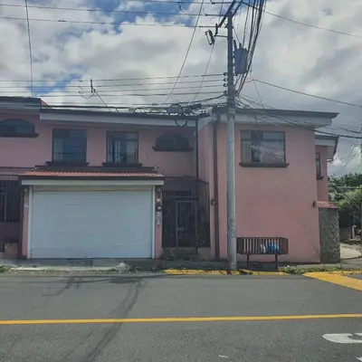 a pink house with a garage on the side of the street at Rooms For RENT, Roommates, Or As BB in Heredia