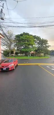 a red car is driving down a street at Rooms For RENT, Roommates, Or As BB in Heredia