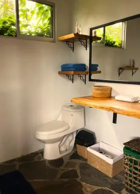 a bathroom with a white toilet and two windows at Casas Kawö y Tulu