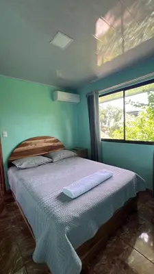 a bed in a blue bedroom with a window at La Casa Tropical in Guayabal