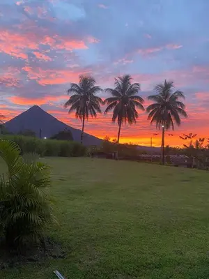 a sunset with palm trees and a mountain in the background at La Casa Tropical in Guayabal