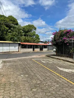 an empty street with a building and flowers on the side at Cabinas en Cañas Guanacaste in Cañas