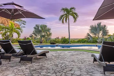 a group of chairs and umbrellas next to a swimming pool at Casa Colinas Pickleball in Playa Grande