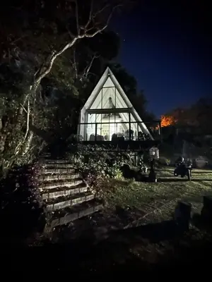 a glass house with stairs in a field at night at Casa Jardin BV