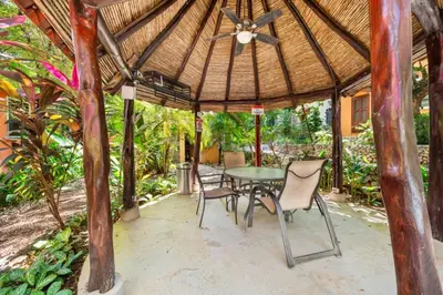 a patio with a table and chairs under a roof at PdM6 Newly Renovated Townhome Steps to the Beach in Tamarindo