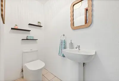 a white bathroom with a toilet and a sink at PdM6 Newly Renovated Townhome Steps to the Beach in Tamarindo
