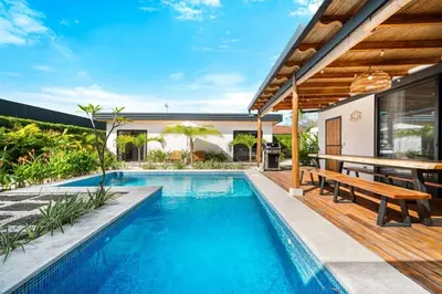 an outdoor swimming pool with a bench and a house at CU21 Stylish 5BR Home with Pool and Casita Close to Beach in Tamarindo