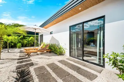 an outdoor patio with a bench and an umbrella at CU21 Stylish 5BR Home with Pool and Casita Close to Beach in Tamarindo