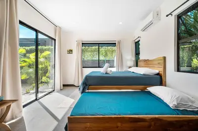 two beds in a room with large windows at CU21 Stylish 5BR Home with Pool and Casita Close to Beach in Tamarindo