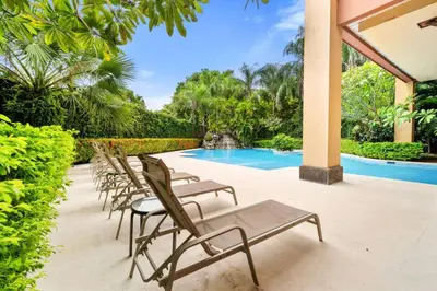 a row of chaise lounge chairs next to a swimming pool at Ocean View Condo in Tamarindo Steps to the Sand in Tamarindo