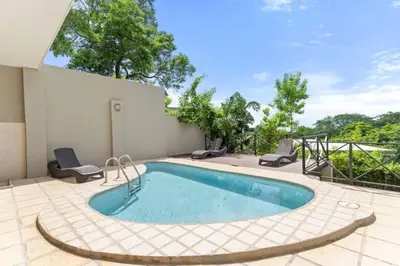 a swimming pool with two chairs and a patio at Stunning Ocean-View 2 BD Overlooking Tamarindo in Tamarindo