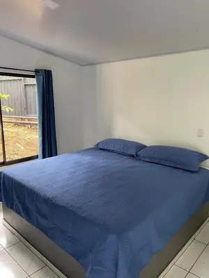a bedroom with a bed with blue sheets and a window at La Casita in San Isidro