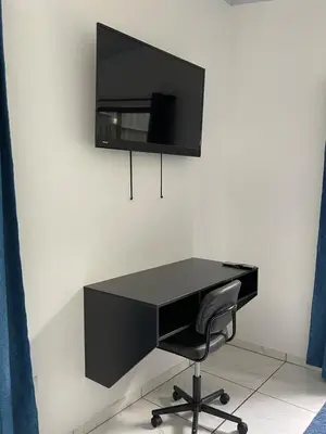 a black desk with a chair and a tv on a wall at La Casita in San Isidro