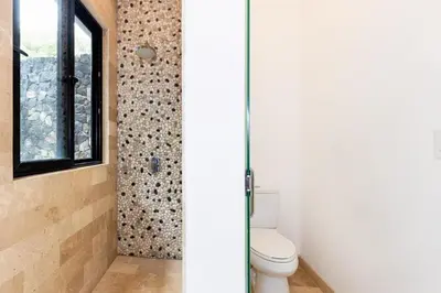 a bathroom with a toilet and a window at Private Pool Luxury Modern House - Llama del Bosque - Reserva Conchal Golf Resort in Playa Conchal
