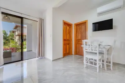 a dining room with a white table and a television at Casa Mango - Villaggio 6 in Potrero
