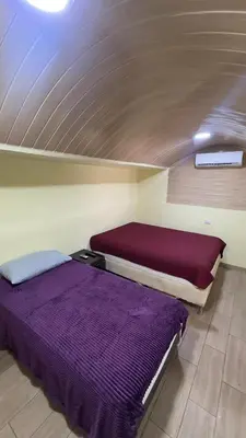 two beds in a small room with purple sheets at Casa Antioquia #4 in Garita