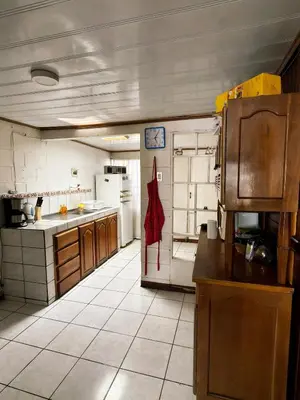 a large kitchen with white tile flooring and wooden cabinets at Casa Brasil in Alajuela City