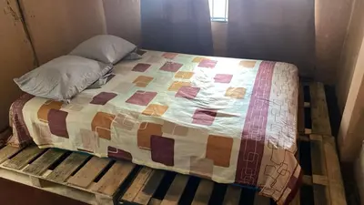 a bed on a wooden platform with a quilt on it at Casa Brasil in Alajuela City
