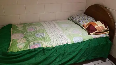 a small bed with a green comforter on it at Casa Brasil in Alajuela City
