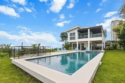 a large swimming pool in front of a house at Breathtaking Views from a Luxury New Villa at Mar a Mar in Jacó