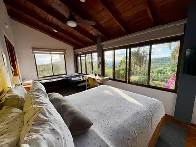 a bedroom with a large bed and large windows at Hotel Honey Bee in Alajuela City