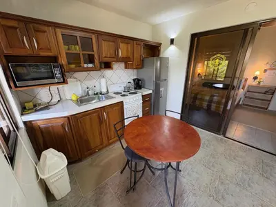 a kitchen with a wooden table and a kitchen with a refrigerator at Hotel Honey Bee in Alajuela City