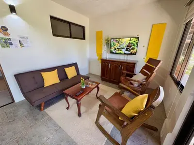 a living room with a couch and a table and chairs at Hotel Honey Bee in Alajuela City